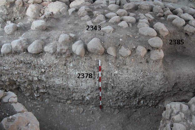 The rampart layers, capped by small-medium stones, looking north; Iron I pits and stone silos cut into the layers. Photo by Tel Abel Beth Maacah CC BY SA 4.0