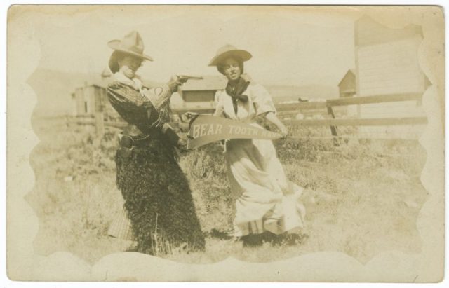 Two Cowgirls with Bear Tooth Ranch Pennant. One of them is holding her pistol.