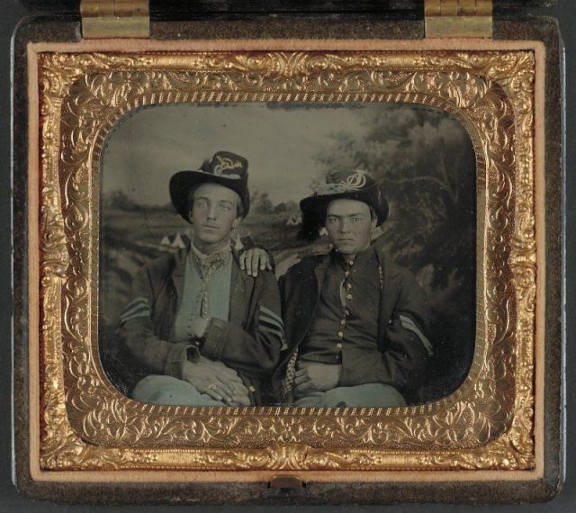 Unidentified sergeant and corporal in Union uniforms in front of painted backdrop.