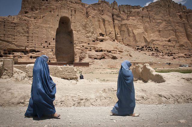 Two women walk past the cavity where one of the ancient Buddhas of Bamiyan, known to locals as the “Father Buddha,” used to stand. Photo by Dvidshub CC By 2.0