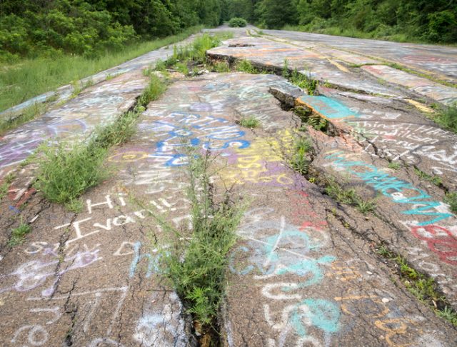 This image shows the extensive damage on PA 61, a closed road that passed through the town of Centralia, which is now overgrown and graffiti covered.