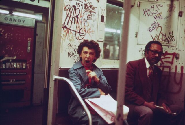 A man and a woman sit inside a subway car