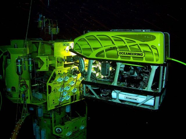 ROV at work in an underwater oil and gas field. The ROV is operating a subsea torque tool (wrench) on a valve on the subsea structure.