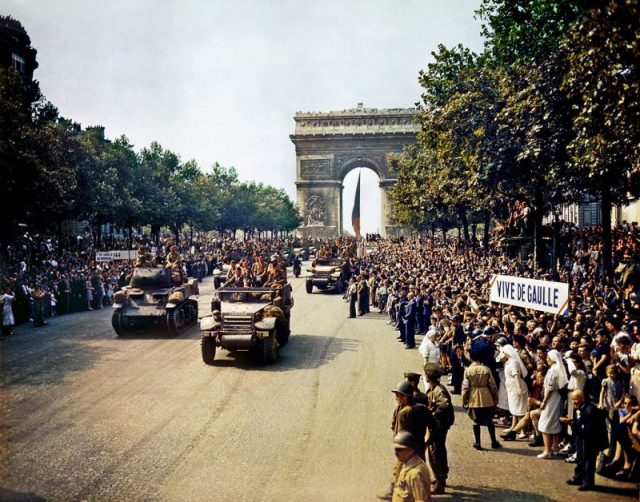Crowds of French patriots line the Champs Elysees to view Free French tanks and half tracks of General Leclerc’s 2nd Armored Division passing through the Arc du Triomphe, after Paris was liberated on August 26, 1944. Among the crowd can be seen banners in support of Charles de Gaulle.