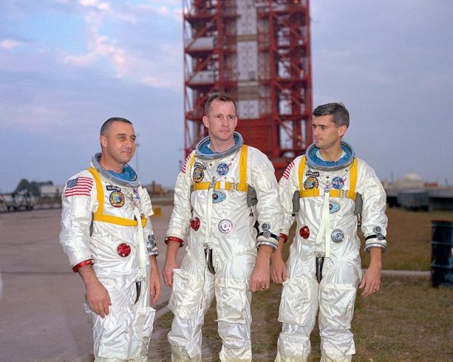 Grissom, White, and Chaffee in front of the launch pad containing their AS-204 space vehicle