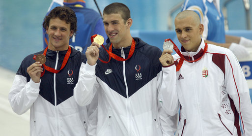 Phelps holds his gold medal on the podium on August 10, 2008. Pictured with Ryan Lochte and László Cseh.