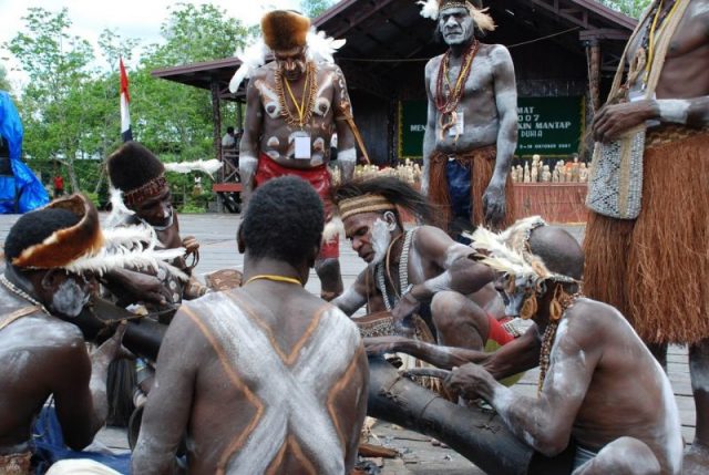 Asmat people performing traditional wood carving in Otsjanep Village.