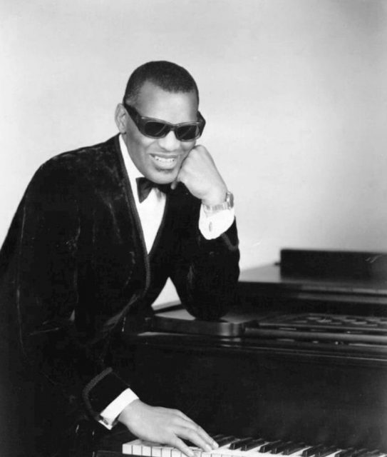 Photo of Ray Charles in one of his classic poses at the piano.