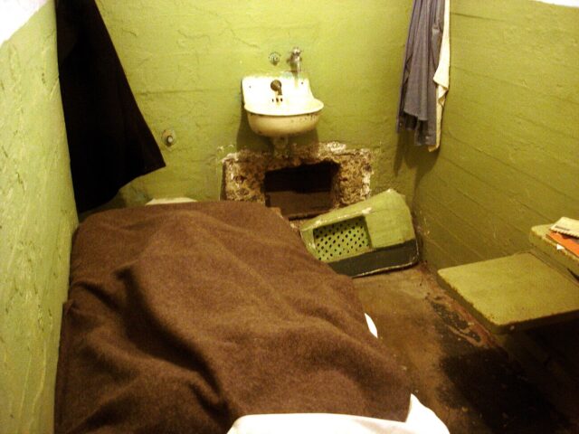 Interior of a prison cell, with a hole cut into the wall