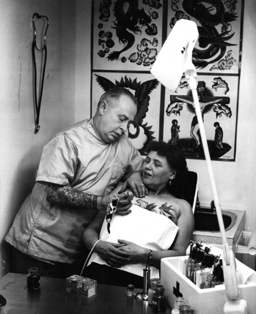 A tattooist painting a bluebird on a woman’s breast, February 1965. Photo by Jim Ryan/Keystone Features/Getty Images