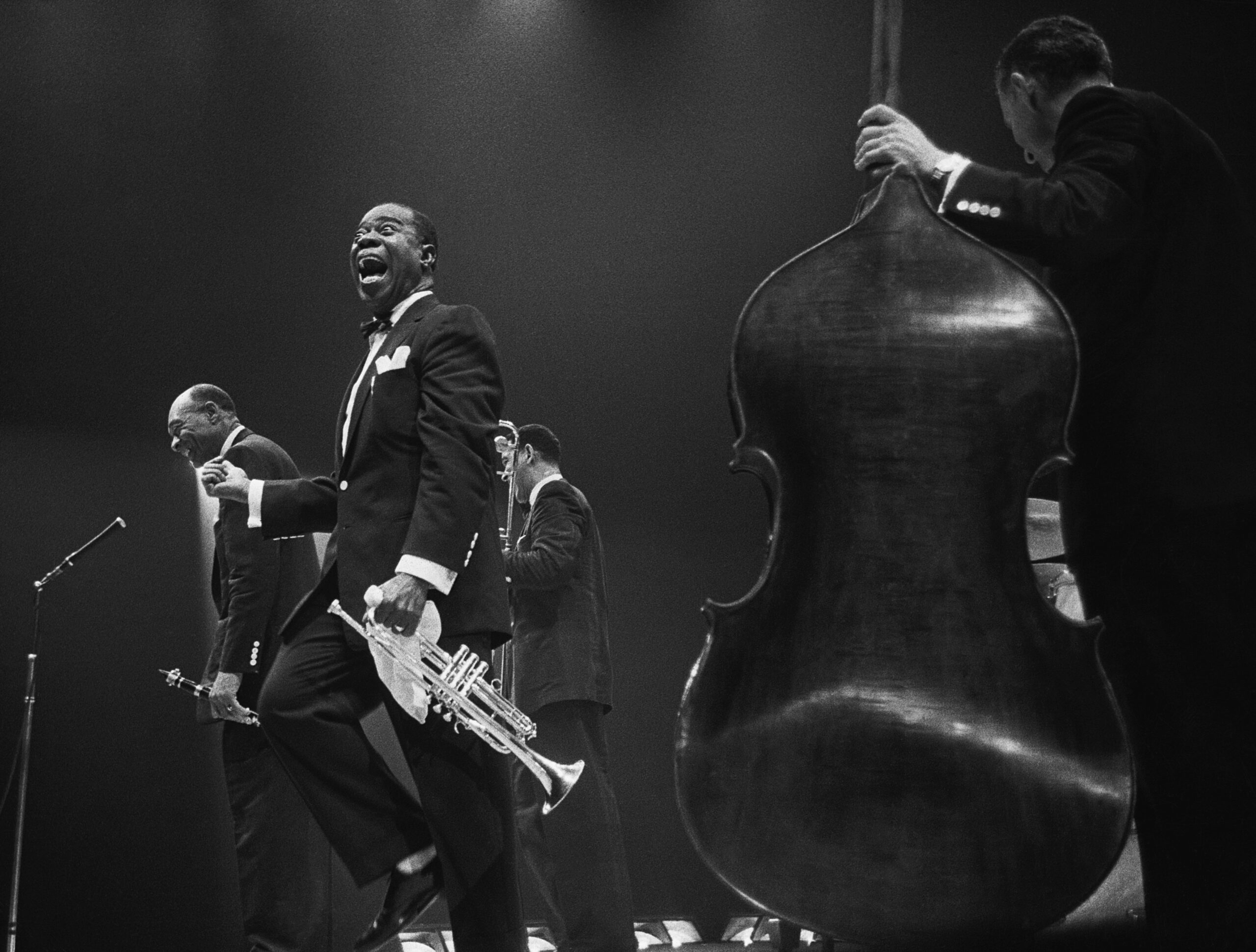 Louis Armstrong in tuxedo with trumpet laughing on stage