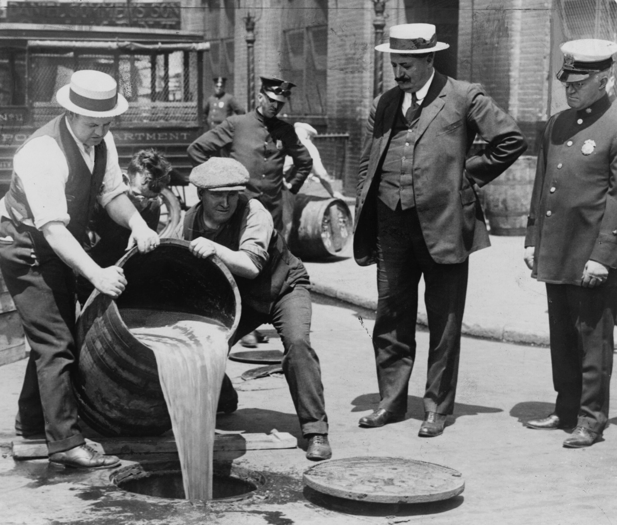 New York City police department supervising alcohol being poured down sewer during prohibition