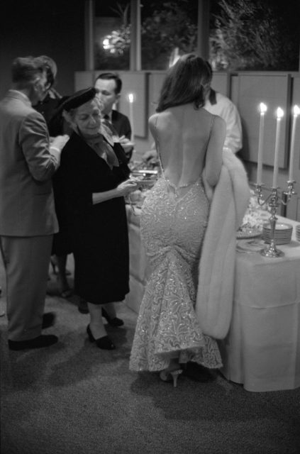 Model and actress Vikki Dougan wearing a low-cut back less gown while an elderly unidentified woman looks at her backside. Los Angeles 1957. Photograph by Ralph Crane/The LIFE Picture Collection