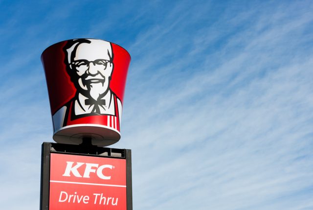 “Cape Town, South Africa – June 21, 2011: A KFC bucket bearing the image of founder Colonel Harland Sanders is placed above a Drive-thru sign at a suburban KFC franchise in Cape Town.”