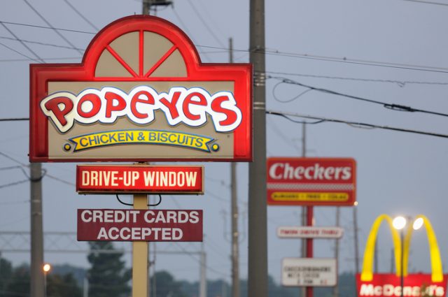 Huntsville, Alabama, USA – August 3, 2011: Illuminated fast food signs at sunrise. Popeyes, Checkers, and McDonalds signs on University Drive in Huntsville, Alabama, just west of Jordan Lane.