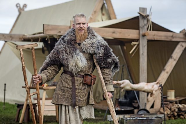 One legged Viking standing in front of a Viking tent.