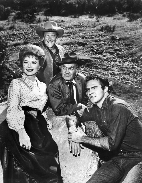 Photo of the main cast for the television program Gunsmoke in 1963. From left Amanda Blake (Miss Kitty), James Arness (Matt Dillon), Milburn Stone (Doc Adams), and Burt Reynolds (Quint Asper).