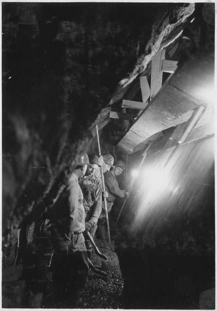 Tamping concrete behind forms in placing side-wall concrete in diversion tunnel lining.