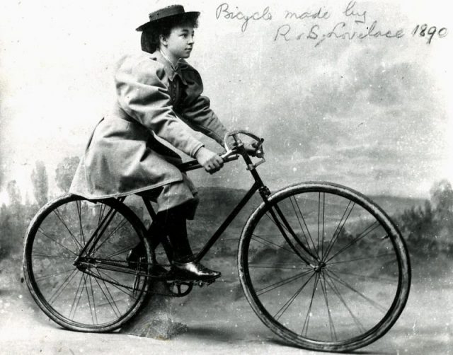 1800s photo of a woman on a man’s bicycle