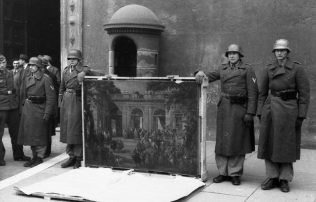 German soldiers of the Hermann Göring Division posing in front of Palazzo Venezia in Rome in 1944 with a picture taken from the Biblioteca del Museo Nazionale di Napoli. Photo by Bundesarchiv, Bild 101I-729-0001-23 / Meister / CC-BY-SA 3.0