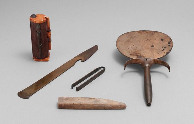 An ancient Egyptian cosmetic set, dating to c. 1550-1458 BC and including (left to right) a kohl tube, a razor, a whetstone, a pair of tweezers, and a mirror.