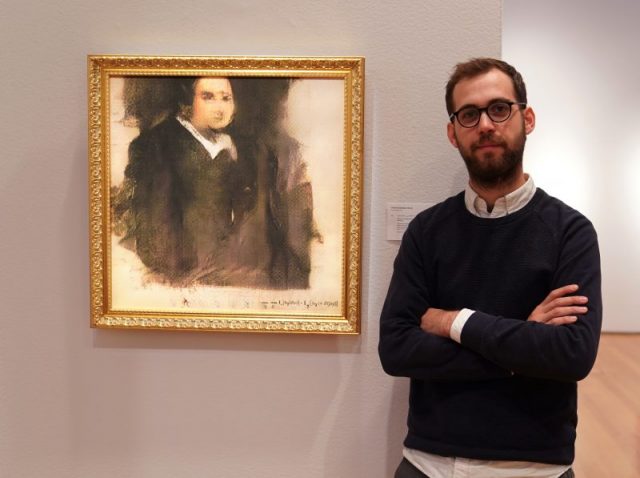 Pierre Fautrel, co-founder of the team of French entrepreneurs called OBVIOUS which produces art using artificial intelligence, stands next to a work of art created by an algorithm titled ‘Portrait of Edmond de Belamy.’ Photo by TIMOTHY A. CLARY/AFP/Getty Images