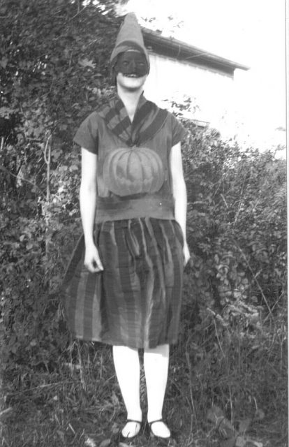 Girl in a Halloween costume in 1928, Ontario, Canada. Can you make out the scary face in the pumpkin?