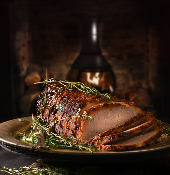 Rolled pork roast with sage and thyme herb garnish.