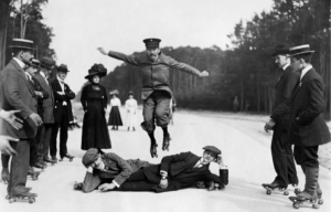 Roller skater are hoping over two men who lying on a ground