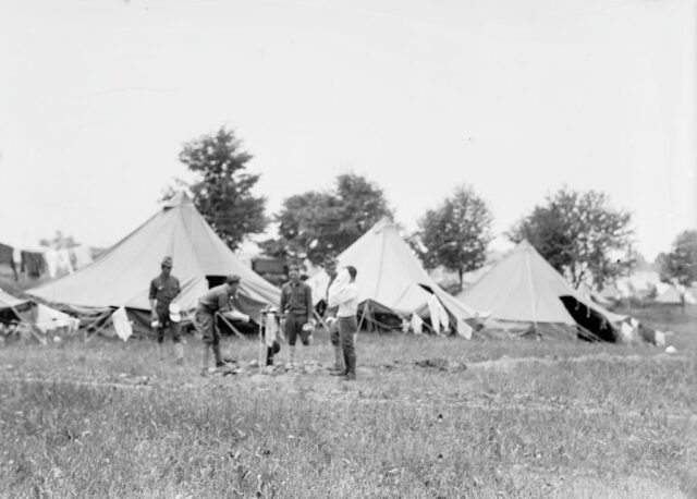 Man standing near a cluster of tents in a grass field