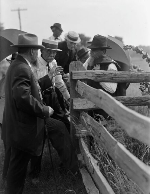 Three American Civil War veterans chatting near a wooden fence