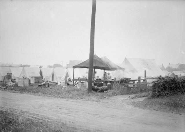 Men standing under a tent that appears to have been turned into a makeshift kitchen