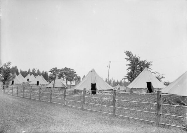 Tents erected behind a wooden fence