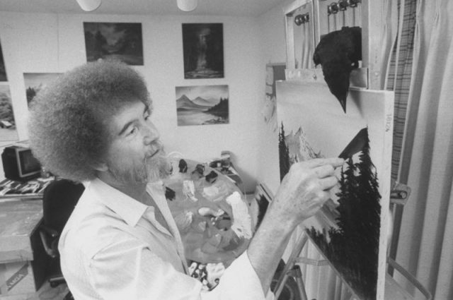 TV painting instructor/artist Bob Ross painting one of his landscapes in his home studio as his pet crow watches closely from its perch on top of the easel. Photo by Acey Harper/The LIFE Images Collection/Getty Images