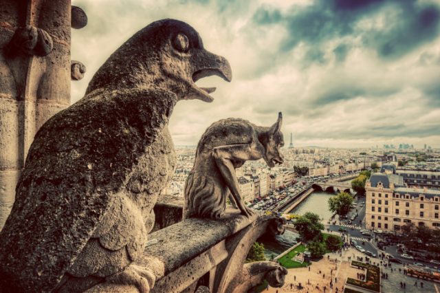 Gargoyles and chimera statues of Notre Dame over Paris, France skyline. Dark clouds, vintage