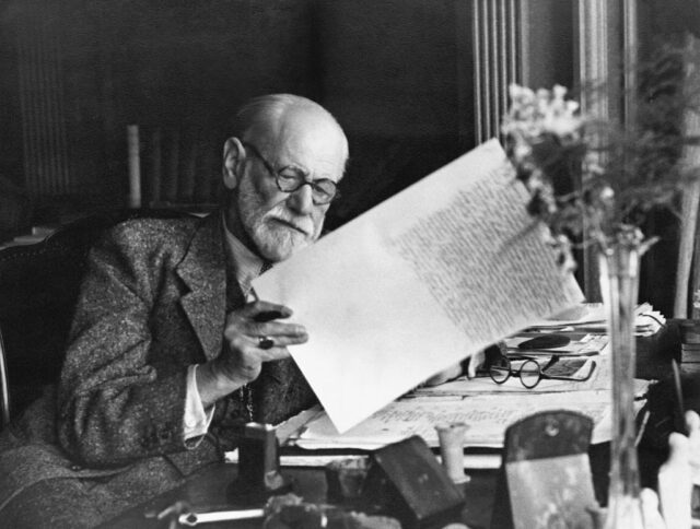 Sigmund Freud reading a manuscript at his desk
