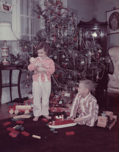 A young boy and a girl playing with their Christmas presents