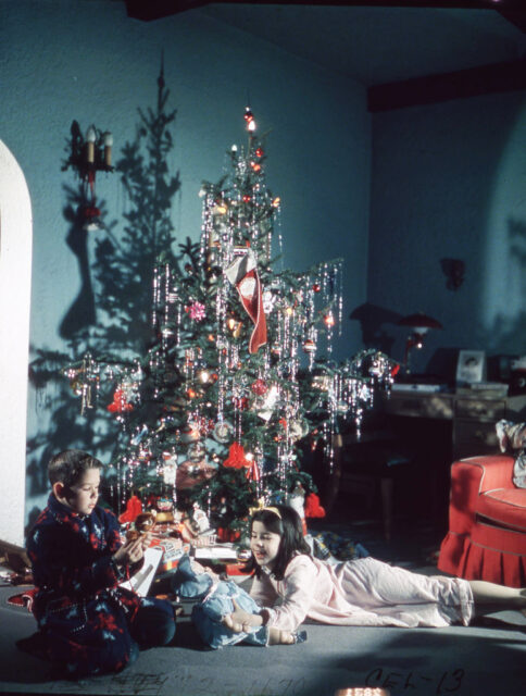Young boy and girl playing with their presents beneath the Christmas tree