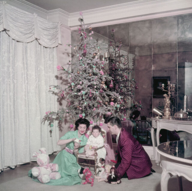 Clyde Newhouse, his wife and his baby sitting in front of a Christmas tree
