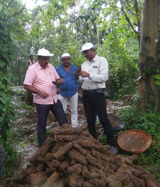 Three men stand around a pile of old rockets.