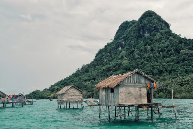 Stilt houses in a Bajau sea gypsy village next to a small island rock outcrop.