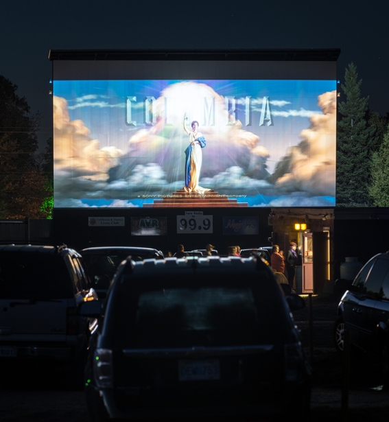 Cambridge, Canada – September 27, 2013: Drive in movie attendees wait in line for their snacks and drinks at the concession stand of the Valley Drive In while the pre-show movie trailers play in the background. Long exposure.