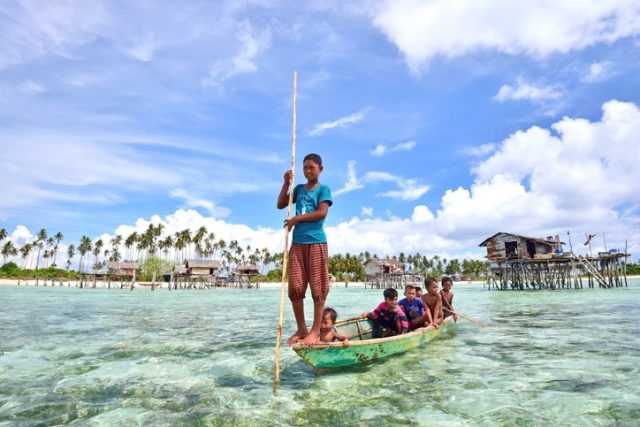 Semporna, Sabah, Malaysia – April 19, 2015: Bajau kids on a boat at a Bajau village in Maiga Island, Semporna, Sabah, Malaysia. They inhabit villages built on stilts in the middle of ocean.