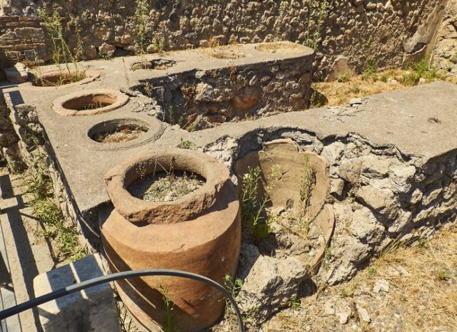 Thermopolium, dolias (jars) detail, of archaeological remains of the street Via Stabiana at Ruins of Pompeii. The city was an ancient Roman city destroyed by the volcano Vesuvius. Pompeii, Campania, Italy.