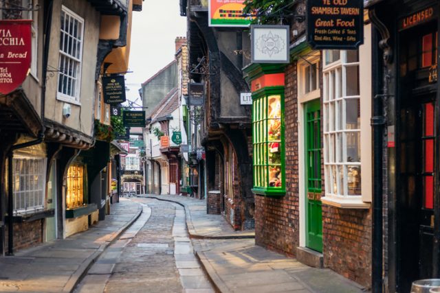 Early morning on the famous narrow medieval street in the historic centre of York, filled with shops, pubs and cafes.