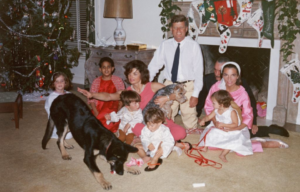 Kennedy family sitting together in front of a fireplace at Christmas