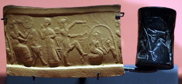 Akkadian cylinder seal impression from Girsu (c. 2340 – 2150 BC) showing a mythological scene. The figure in the center appears to be a god, perhaps Gilgamesh, who is bending the trunk of a tree into a curve as he chops it down. Underneath the tree, a god ascending from the Underworld hands a mace-like object to a goddess. Photo by Applejuice CC BY-SA 4.0