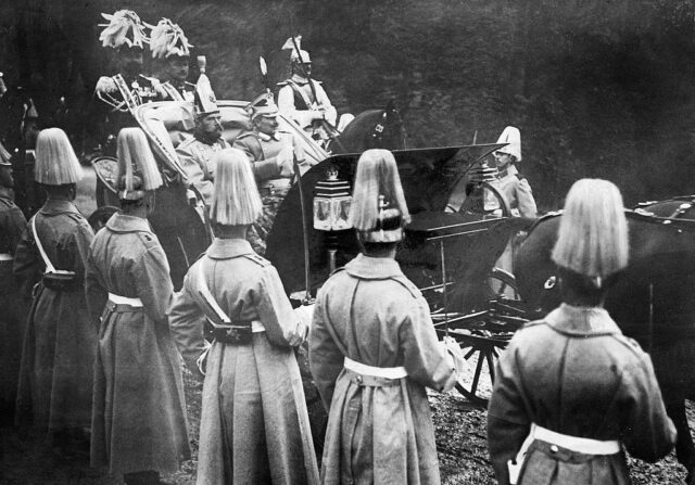 Tsar Nicholas II of Russia and Kaiser Wilhelm of Germany riding together in a carriage while people stand along the side of the road