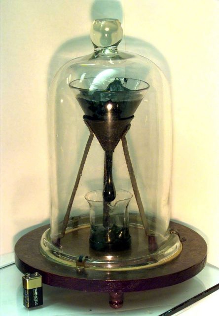 Picture of the Pitch Drop Experiment at the University of Queensland, with 9-volt battery for size comparison. Photo by John Mainstone, University of Queensland CC BY SA 3.0