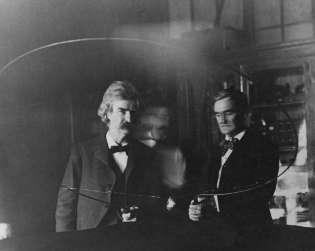 Serbian-American inventor and engineer Nikola Tesla (1856 – 1943, blurred at centre) performs an electrical experiment for writer Samuel Clemens, aka Mark Twain (1835 – 1910, left) and actor Joseph Jefferson (1829 – 1905), 1894. Photo by Kostich/FPG/Archive Photos/Getty Images